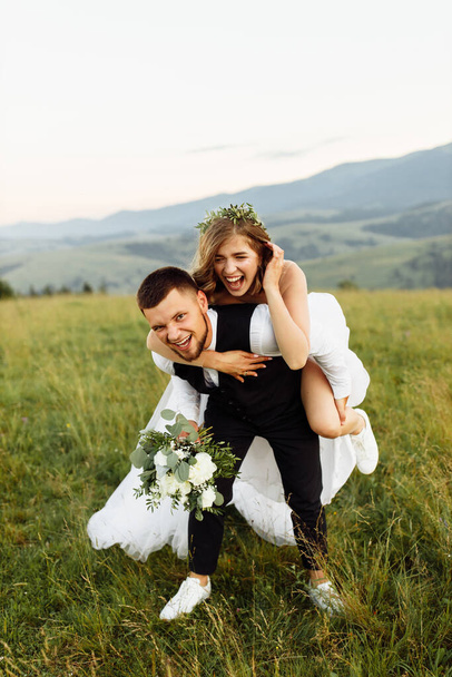 beautiful young wedding couple in love posing on the background of the mountains - Fotografie, Obrázek