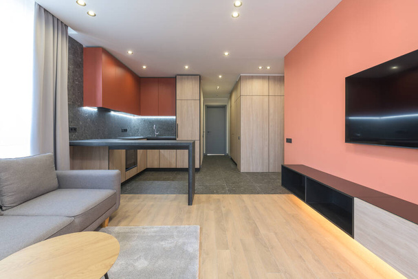 Сучасний дизайн житлової квартири з кольоровими стінами Марсала, сірим диваном і дерев'яною кухнею. - Фото, зображення