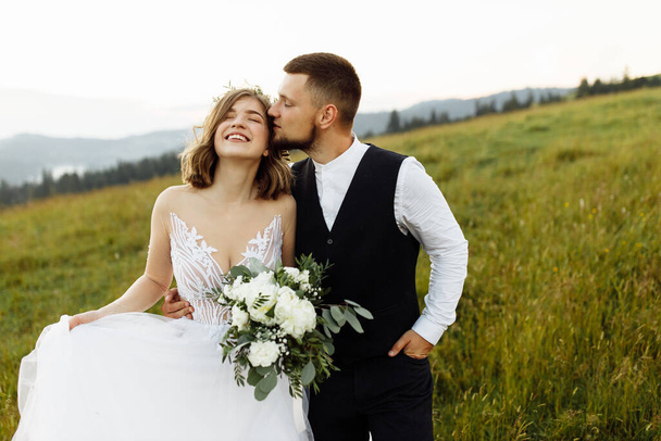 beautiful young wedding couple in love posing on the background of the mountains - Fotoğraf, Görsel