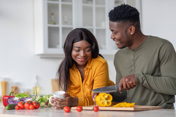 Retrato de cónyuges negros románticos preparando comida saludable juntos en la cocina - Foto, imagen