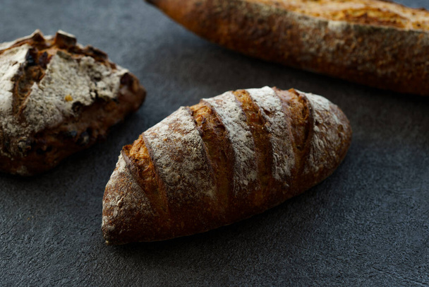 Různé druhy chleba na tmavém stole - Fotografie, Obrázek