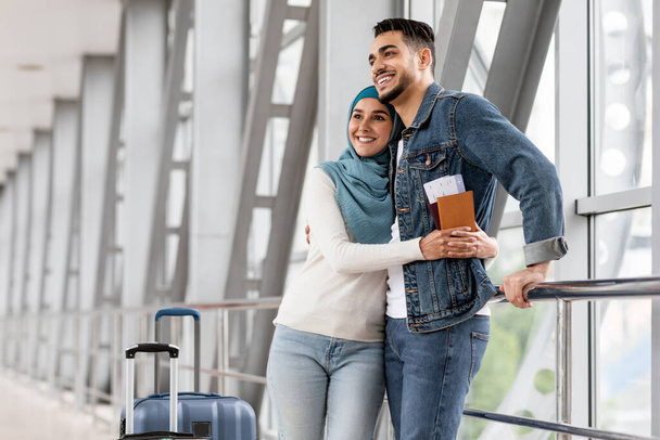 Retrato de casal islâmico alegre à espera de voo no terminal do aeroporto - Foto, Imagem