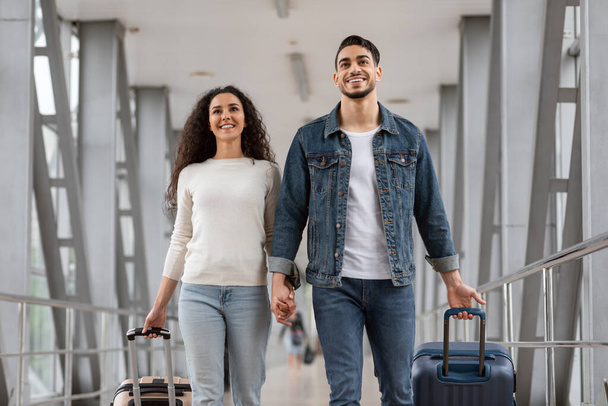 Portrait Of Positive Millennial Arab Couple Walking At Airport With Luggage - Foto, Imagen