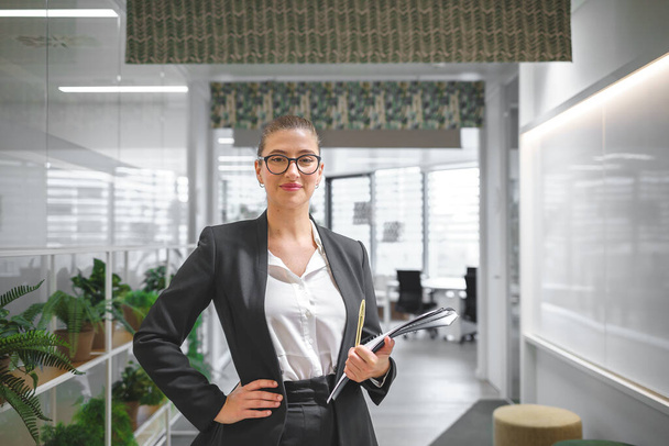 Уверенная деловая женщина, стоящая в холле на рабочем месте - Фото, изображение