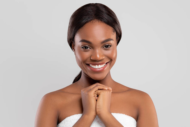 Cheerful pretty millennial african american woman with perfect skin in towel isolated on gray background, studio - Photo, Image
