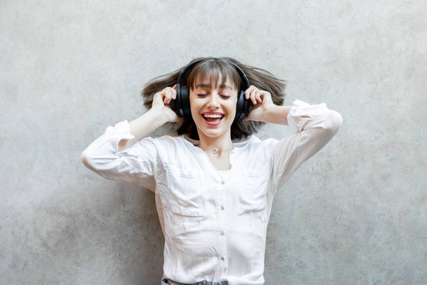 Γυναίκα ακούγοντας μουσική σε ασύρματα ακουστικά στο παρασκήνιο - Φωτογραφία, εικόνα