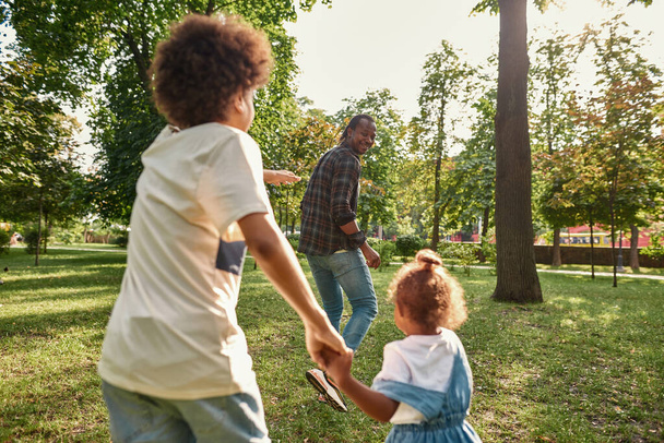 Young black family playing on lawn in green park - Foto, imagen