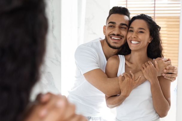 Affectionate Millennial Couple Looking At Mirror And Cuddling In Bathroom - Photo, Image