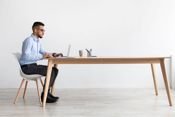 Arab férfi használ laptop ül íróasztal az irodában - Fotó, kép