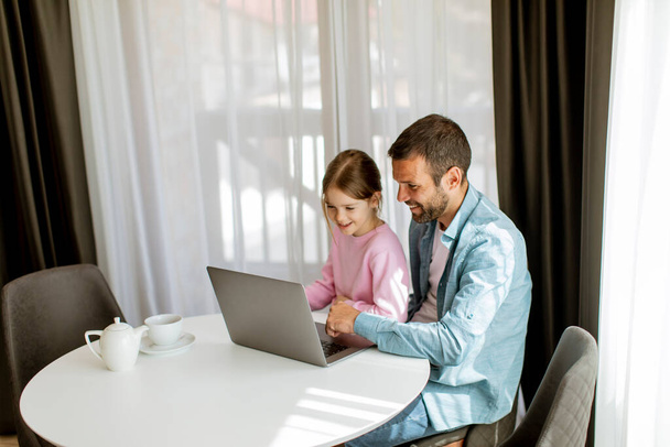 Father and daughter using laptop computer together in the room - Photo, image