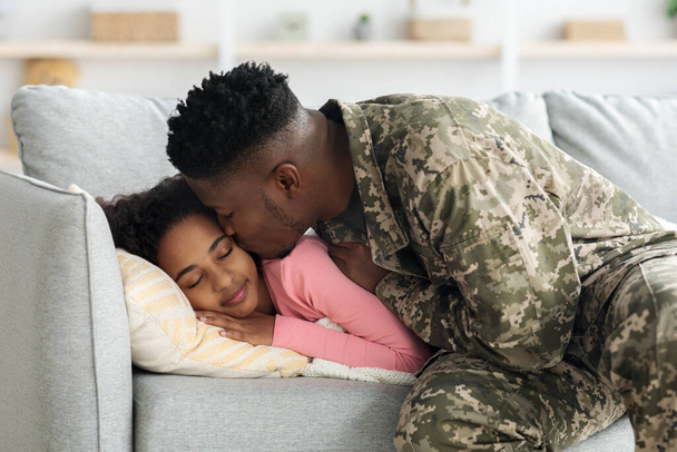 Black man soldier back for military service, kissing sleeping daughter - Photo, Image
