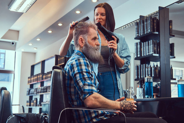 Salon de coiffure moderne et femme séchant les cheveux du vieil homme - Photo, image