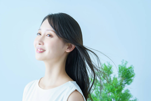 Asiática joven mujer con aleteo pelo y una sonrisa - Foto, imagen