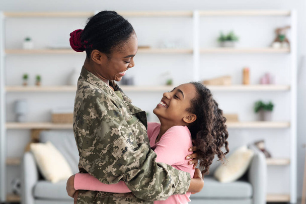 Αγαπώντας την μαύρη μητέρα στρατιώτη που δένεται με την χαριτωμένη κόρη της - Φωτογραφία, εικόνα