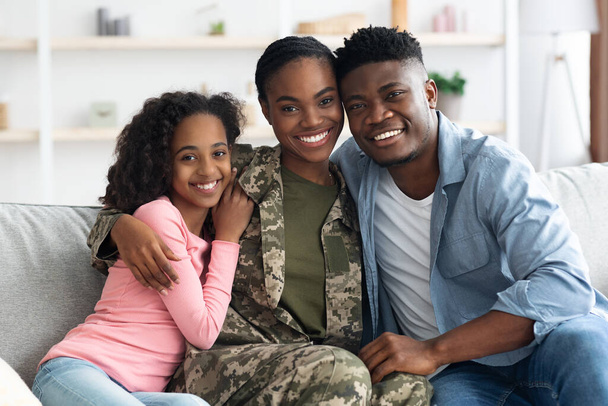Family portrait of happy black kid, husband and military wife - 写真・画像