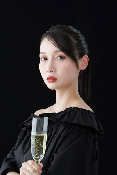 Jonge vrouw met champagne glas en zwarte achtergrond - Foto, afbeelding