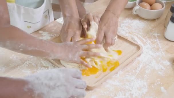 Closeup hands of African American family with daughter add egg to flour and thresh for cooking with father and mother together in the kitchen at home, parent and little child preparing food with fun. - Footage, Video
