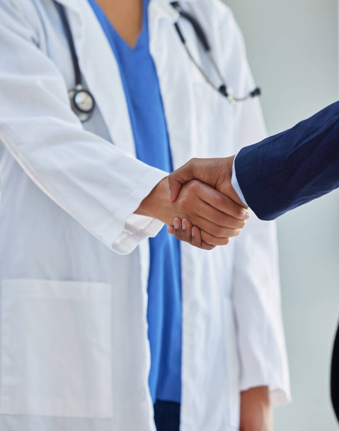 Transforming healthcare with a trusted partner. Cropped shot of a doctor shaking hands with a businessman in a hospital. - Photo, Image