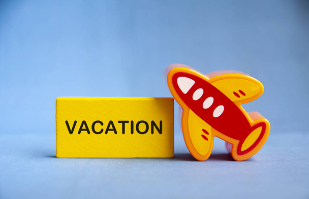Testo di vacanza su blocco di legno giallo con aereo giocattolo. Concetto di viaggio - Foto, immagini