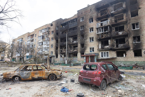 Irpenstad, Oekraïne, 11 april 2022. Oorlog van Rusland tegen Oekraïne. Uitgebrande auto tegen de achtergrond van een uitgebrand huis - Foto, afbeelding