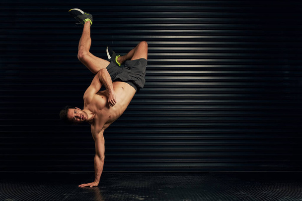 Lemme break it down for you. Studio portrait of a shirtless and well built man breakdancing against a dark background. - Foto, Imagem
