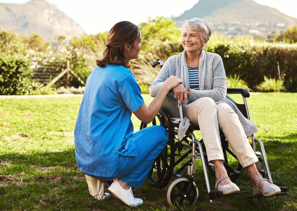 新鮮な空気で出来ると思ってた。車椅子の高齢患者と一緒に外の若い女性看護師の作物のショット. - 写真・画像