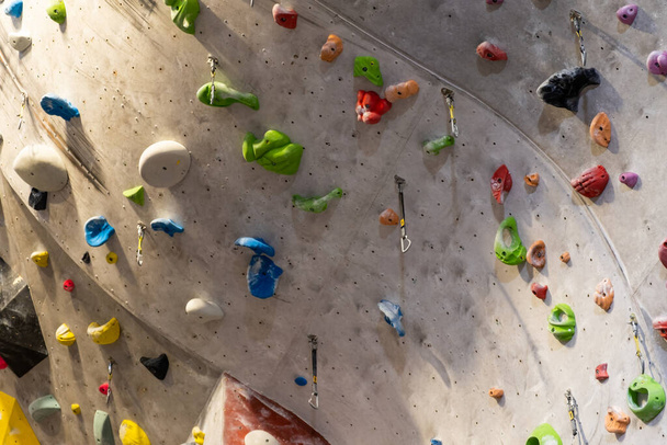 Artificial rock climbing wall with various colored grips - 写真・画像