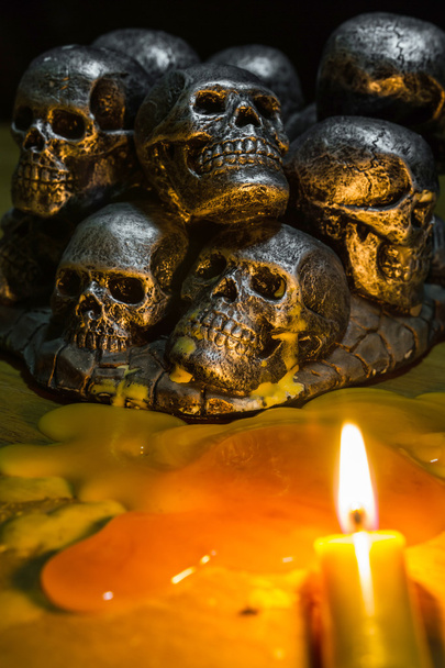 calaveras con velas ardiendo sobre fondo de madera en la oscuridad
  - Foto, Imagen