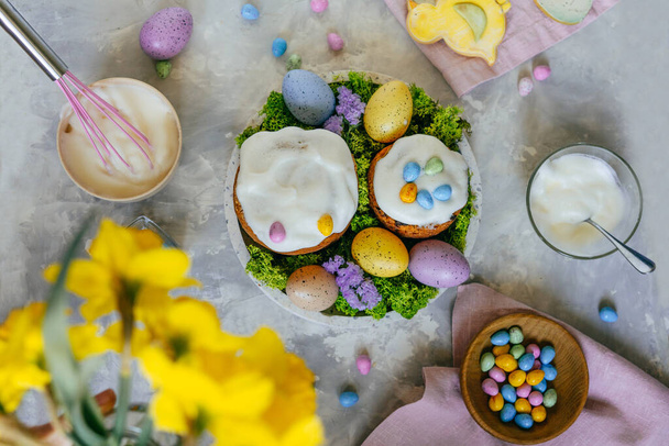 Vista superior de pasteles de Pascua decorados con mini huevos de chocolate en la mesa gris de hormigón. Puesta plana. - Foto, Imagen