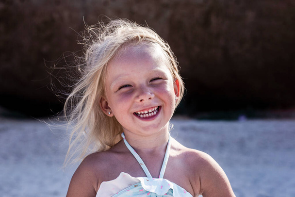 Cheerful smiling child blonde girl in swimsuit on the beach  - Foto, Imagen