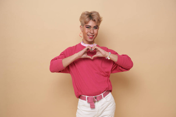 Juventude asiática transgênero LGBT olhando para a câmera enquanto posando isolado sobre fundo de cor nua.  - Foto, Imagem