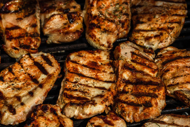 Grilling pork steaks. Delicious meat steaks close up cooking on the barbecue grill - Photo, Image