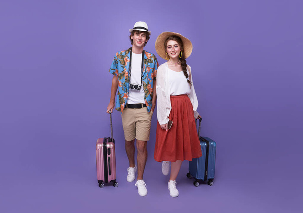 紫色の背景に隔離された休日に旅行する荷物を持つ幸せなカップルの観光客。休暇の時間 - 写真・画像