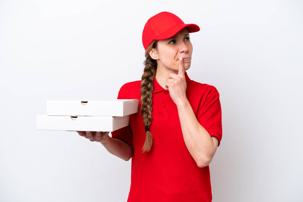 livreuse de pizza avec uniforme de travail ramasser des boîtes de pizza isolées sur fond blanc ayant des doutes tout en regardant vers le haut - Photo, image