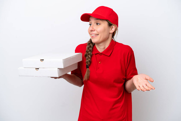 Доставка пиццы женщина в рабочей форме подобрав коробки пиццы изолированы на белом фоне с удивлением выражение лица, глядя в сторону - Фото, изображение