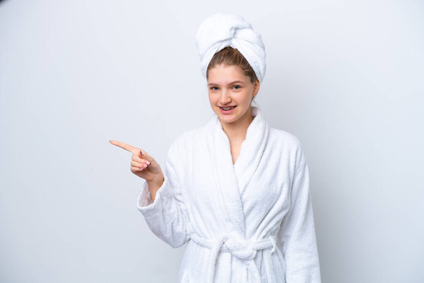 Teenager Russian girl in a bathrobe isolated on white background pointing finger to the side - Valokuva, kuva
