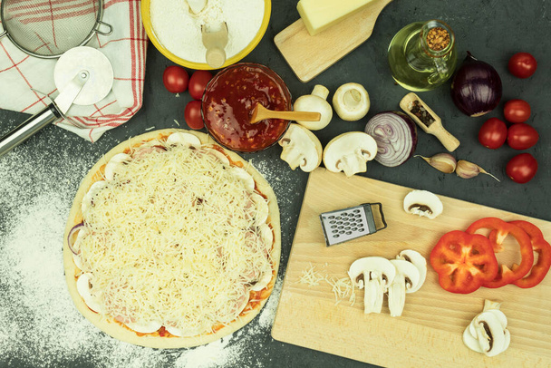 Hozzávalók az asztalon a pizza készítéshez. Pizzakészítési folyamat: tészta, sodrófa, tojás, vaj és búzaliszt fából készült asztalon. Háttér szöveges szöveggel - Fotó, kép