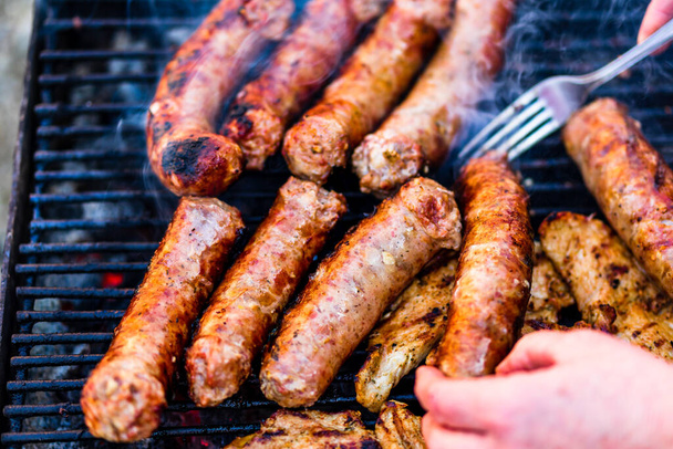 Grillworstjes en varkenskoteletjes op barbecue grill. BBQ in de tuin - Foto, afbeelding