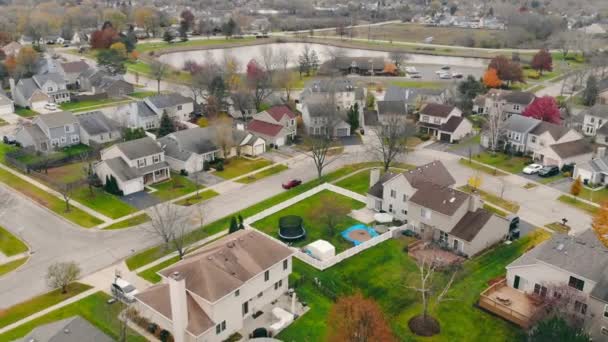 Lakóházak a külvárosi kerületben a város, a tó a háttérben. Légi felvétel a külváros drónjáról, kis hangulatos házakkal ősszel, Chicago külvárosában, Illinois államban, USA-ban. A külvárosi élet fogalma - Felvétel, videó