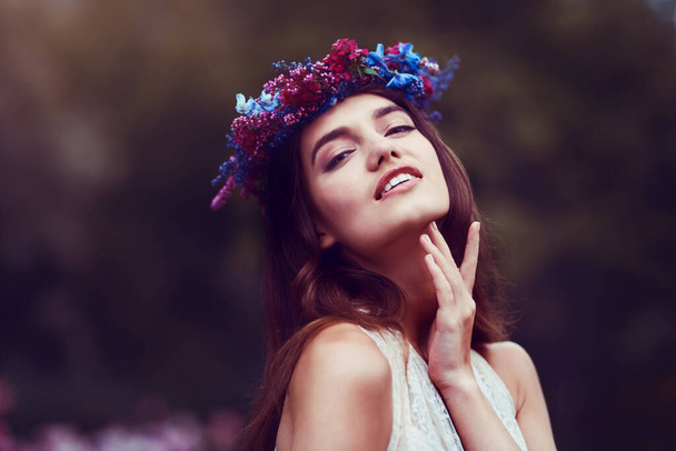 Jak pięknie po prostu być. Portret pięknej młodej kobiety noszącej wieniec z kwiatową głową na zewnątrz. - Zdjęcie, obraz