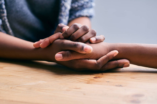 Podporovat kamaráda. Vystřižený snímek dvou lidí držících se za ruce v pohodlí na stole. - Fotografie, Obrázek
