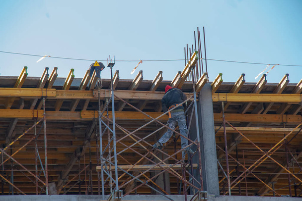 Ένας εργαζόμενος προετοιμάζει τις εργασίες για μια σύγχρονη μεταλλική-τσιμεντένια κατασκευή ενός κτιρίου κατοικιών. - Φωτογραφία, εικόνα