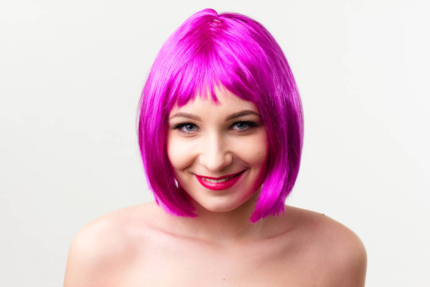 Face of a young woman with bright makeup on a pink background with gathered hair in a smooth ponytail. - Фото, зображення