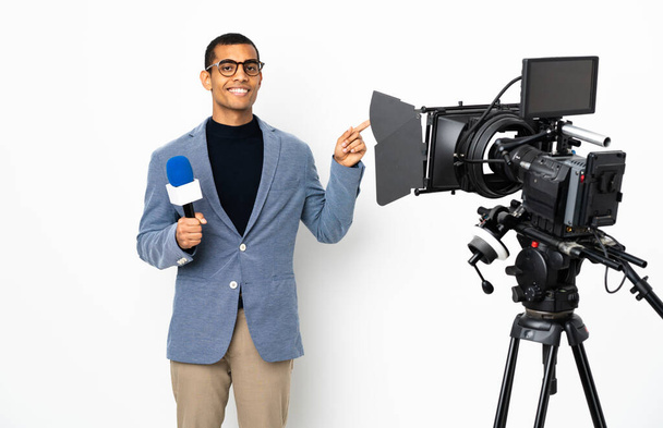 Riporter afro-amerikai férfi kezében egy mikrofon és riportot hírek izolált fehér háttér mutogatott ujjal oldalra - Fotó, kép