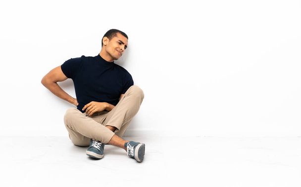 Afroamerykanin siedzący na podłodze cierpiący na bóle pleców za wysiłek - Zdjęcie, obraz