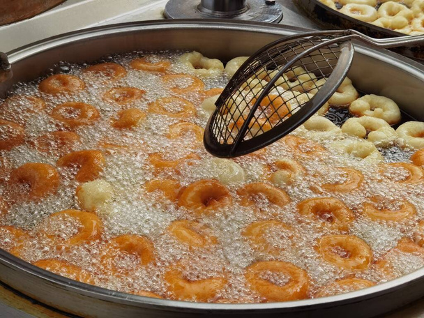 Gold brown round candies in a big pot in oil - Photo, Image