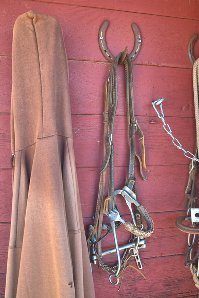Carrinhos de cavalo e selas pendurados em uma sala de tack em um rancho remoto - Foto, Imagem