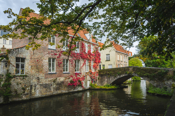 The historical city center of Bruges with medieval brick architecture reflected in the water of a canal - Zdjęcie, obraz