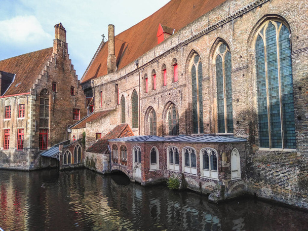 The historical city center of Bruges with medieval brick architecture reflected in water of a canal  - Foto, imagen