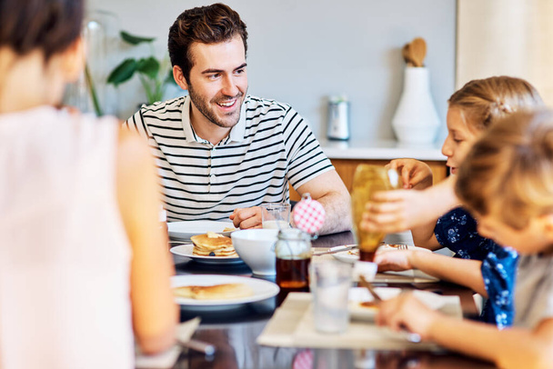 Nagyon élvezik a közös étkezést. Egy családról, akik együtt reggeliznek otthon.. - Fotó, kép